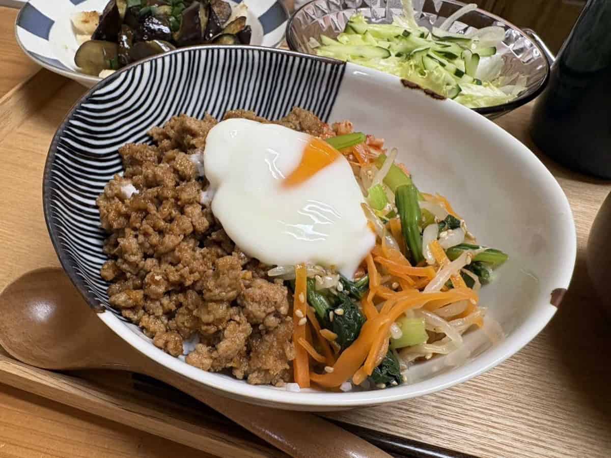 A bowl of bibimbap on the dinner table with a runny egg yolk