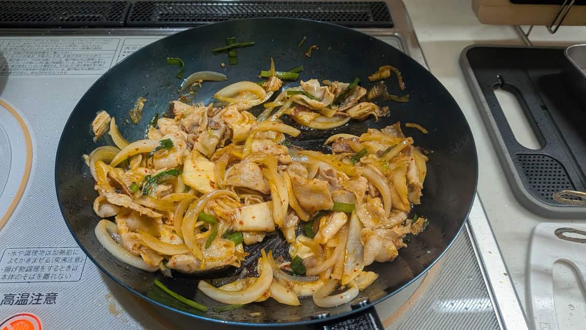 Finished buta kimchi tossed together in the frying pan, pork and onion coated in red kimchi seasoning