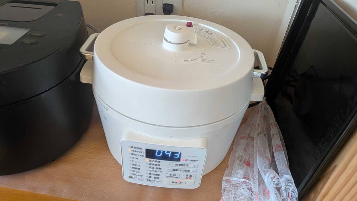 A white Iris Ohyama electric pressure cooker running on a kitchen counter