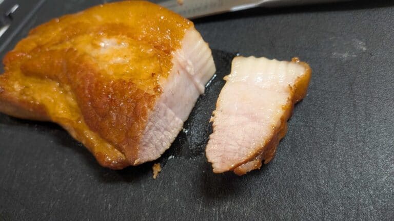 Sliced Japanese chashu pork belly on a cutting board, showing the glossy braised exterior and tender interior