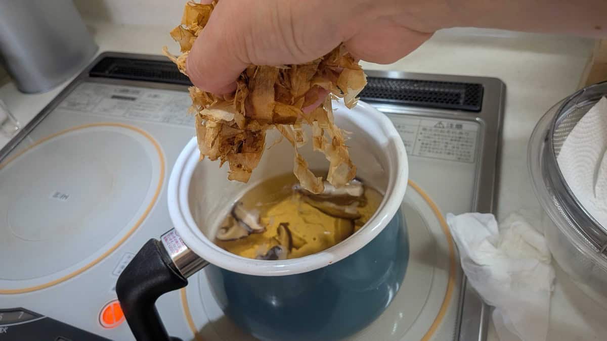 Adding a handful of katsuobushi bonito flakes to the dashi pot