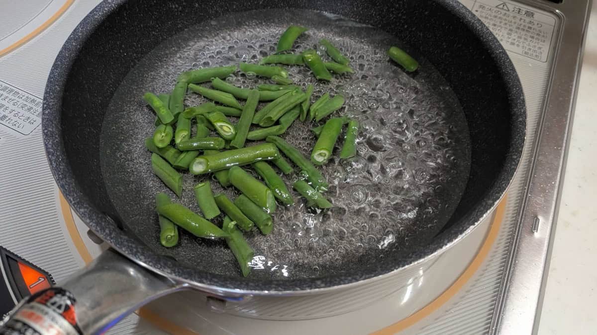 Cut green beans boiling in a small pan of salted water