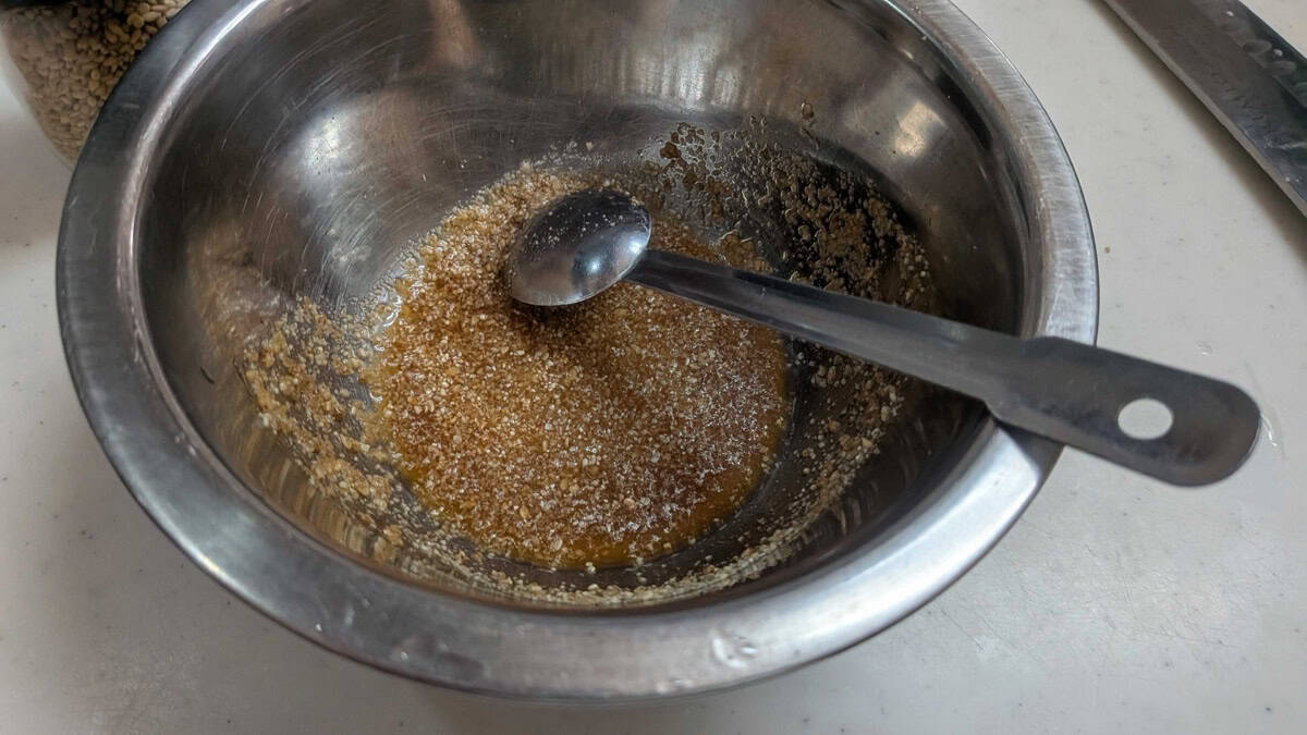 Ground sesame seeds mixed with sugar and soy sauce into a paste in a metal bowl