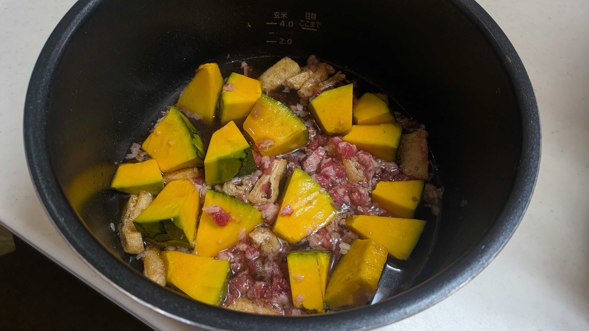 Kabocha chunks, beef, and aburaage strips in the pressure cooker pot with the simmering broth before cooking