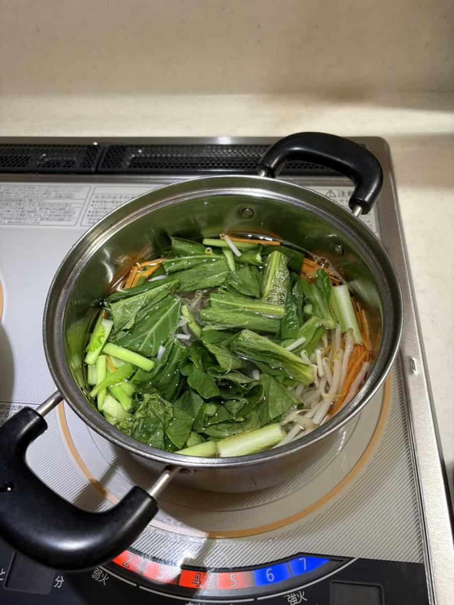 Komatsuna, carrot, and bean sprouts blanching in a pot of hot water