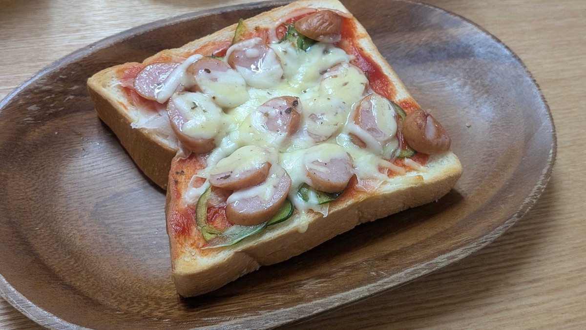 Close-up of finished pizza toast with golden melted cheese and rounds of sliced sausage