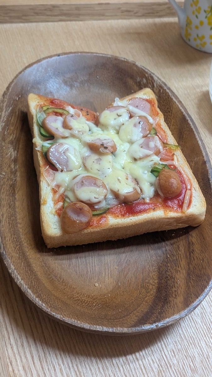 Japanese pizza toast on a wooden plate — thick bread topped with ketchup, onion, green pepper, sliced wiener sausage, and melted cheese