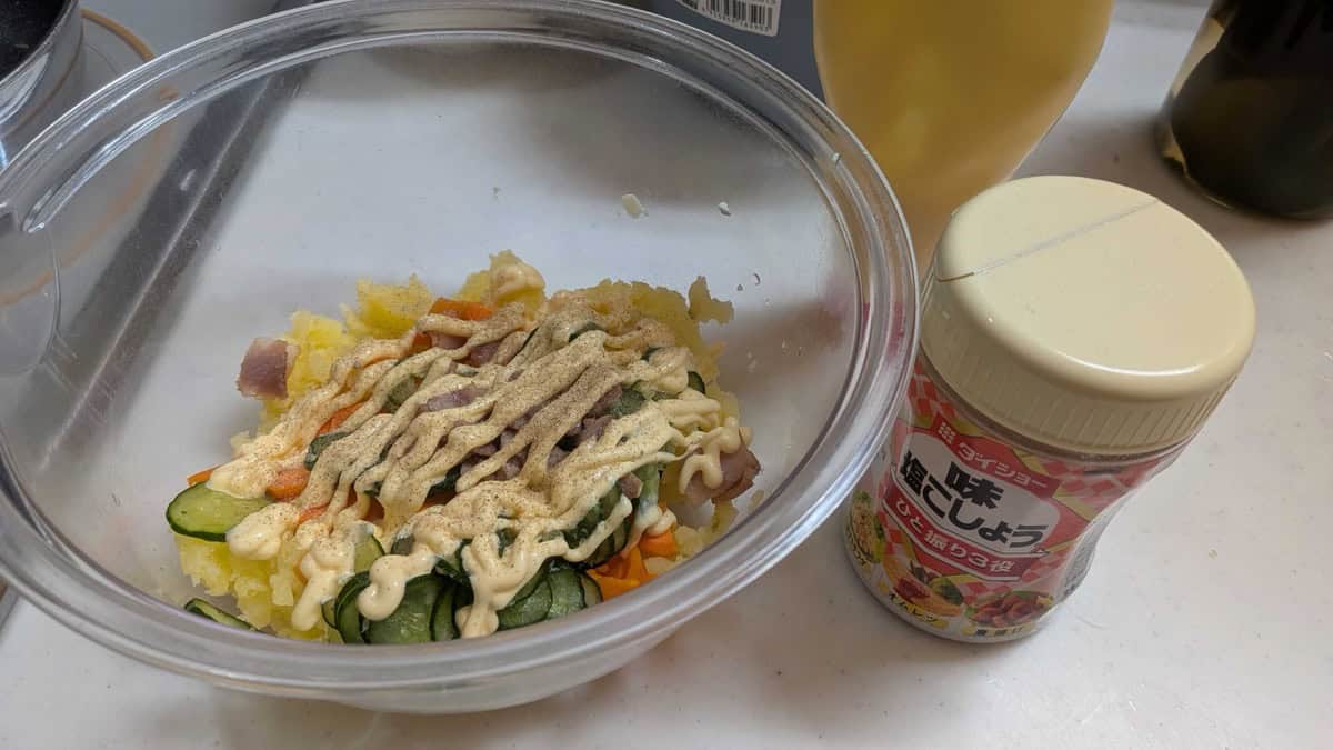 Japanese mayonnaise and salt and pepper being added to the potato salad