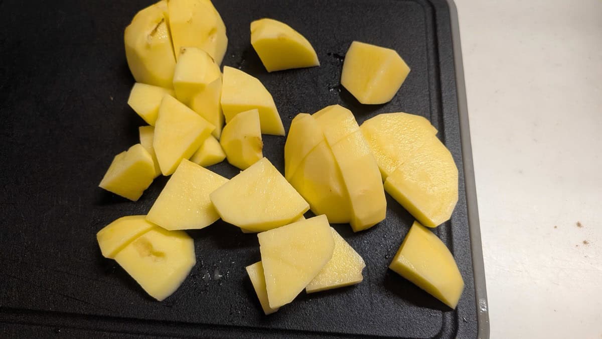 Peeled potatoes cut into chunks on a cutting board