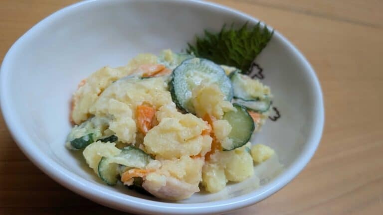 Japanese potato salad in a white bowl with a shiso leaf — creamy mashed potato with carrot, cucumber, and ham