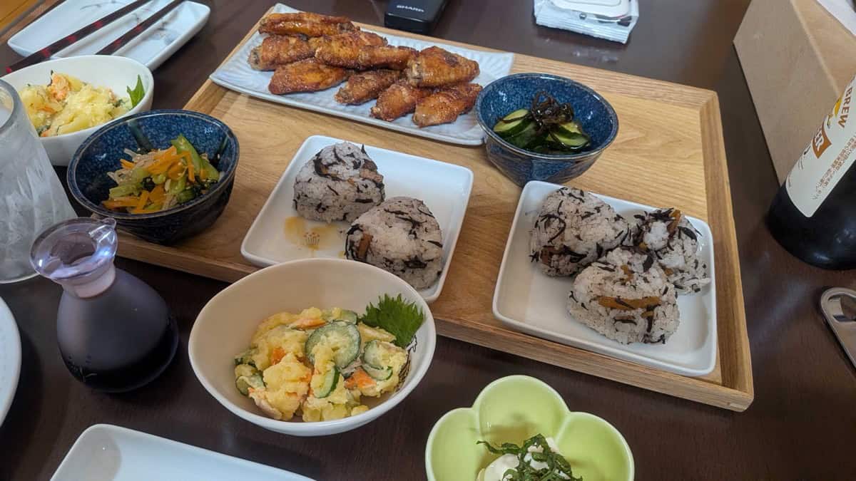 Japanese potato salad as part of a home-style dinner with tebasaki wings, onigiri, and pickles