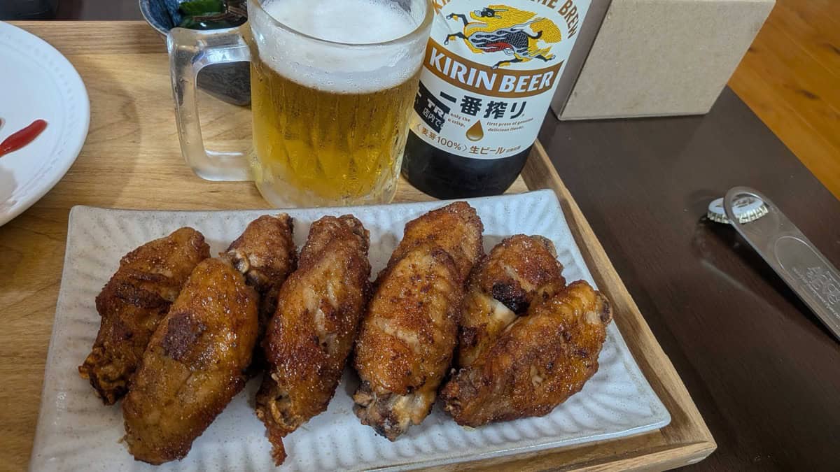 A plate of Nagoya-style tebasaki chicken wings served with a mug of Kirin beer