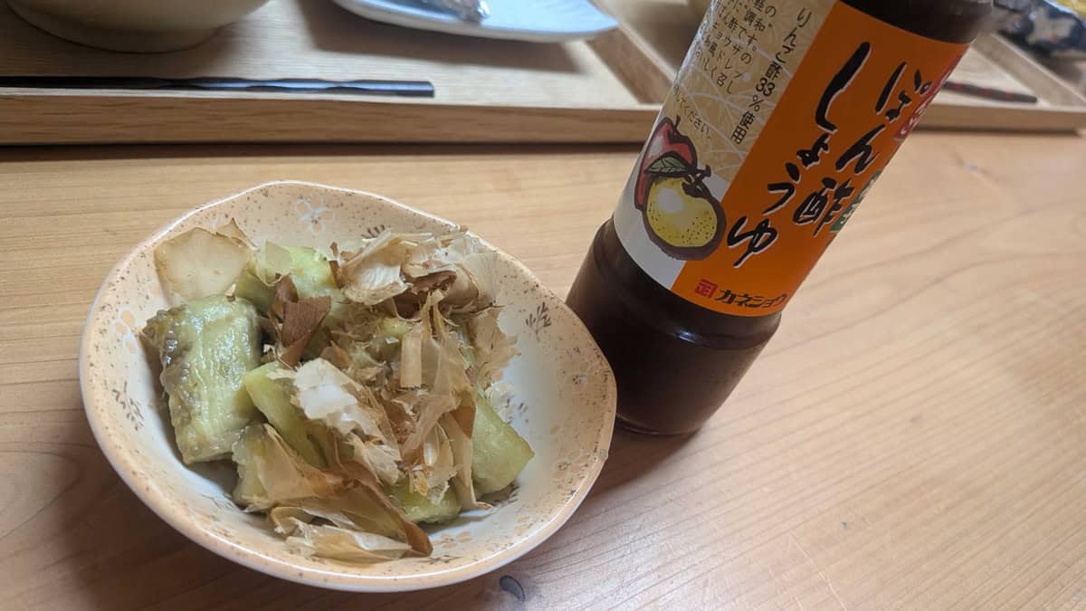 Yaki nasu in a small bowl next to a bottle of apple-vinegar ponzu shoyu on the dinner table