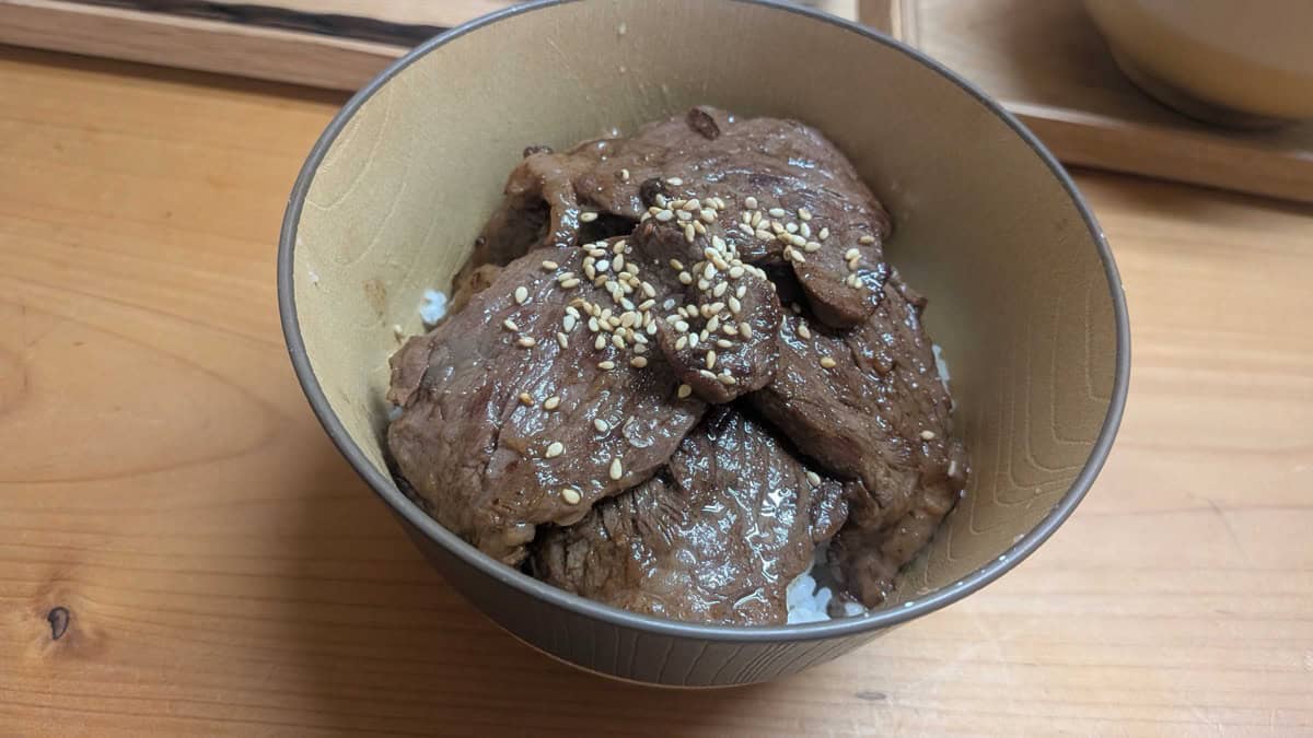 Yakiniku don — Japanese BBQ beef over rice in a wooden bowl, topped with toasted sesame seeds