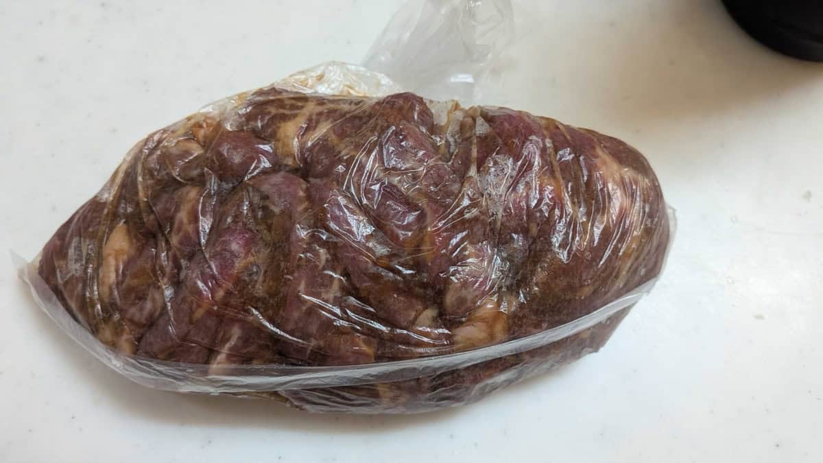 Sealed bag of beef marinating in yakiniku sauce, the meat darkened by the marinade