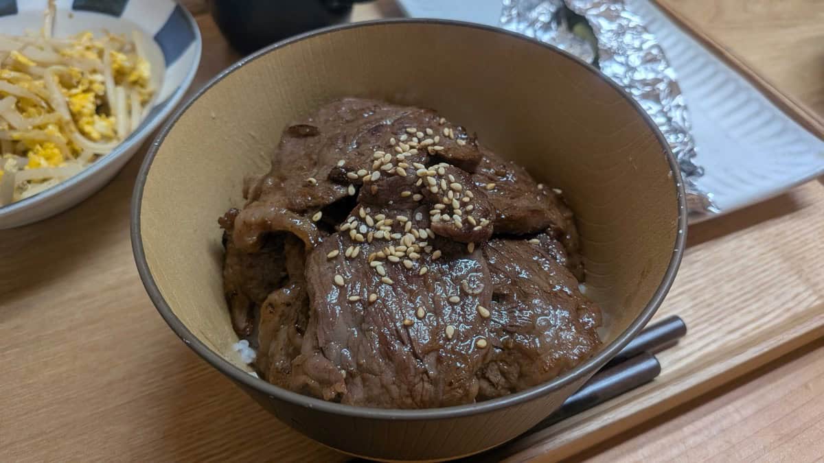 Yakiniku don served at the dinner table with a side of bean sprouts and egg