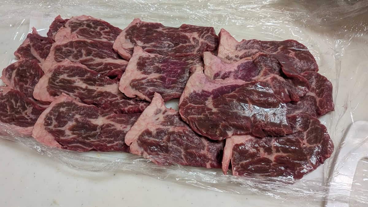 Raw thin-sliced beef for yakiniku laid out on plastic wrap