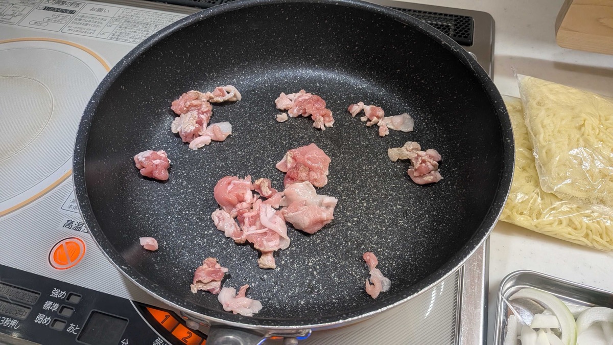 Sliced pork frying in a pan on an induction cooktop