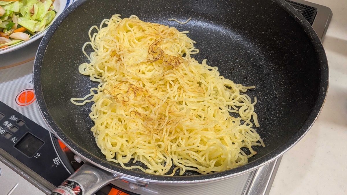 Yakisoba noodles frying and browning in the pan on their own