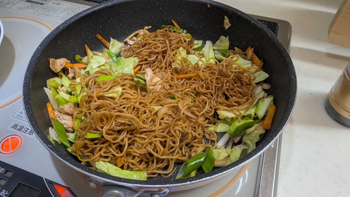 The pork and vegetables mixed back into the sauced yakisoba noodles in the pan