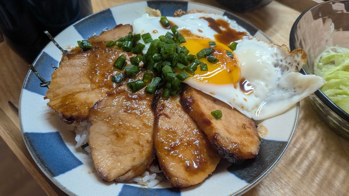 Chashu don served with a bowl of shredded lettuce on a wooden tray