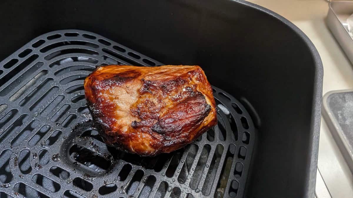 Browned and glazed pork loin chashu resting in an air fryer basket after cooking