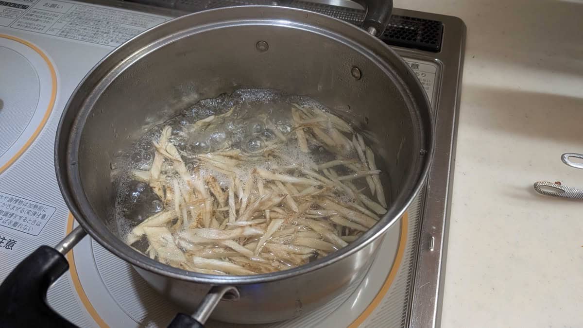 Burdock root matchsticks boiling in a stainless steel pot on an induction stove