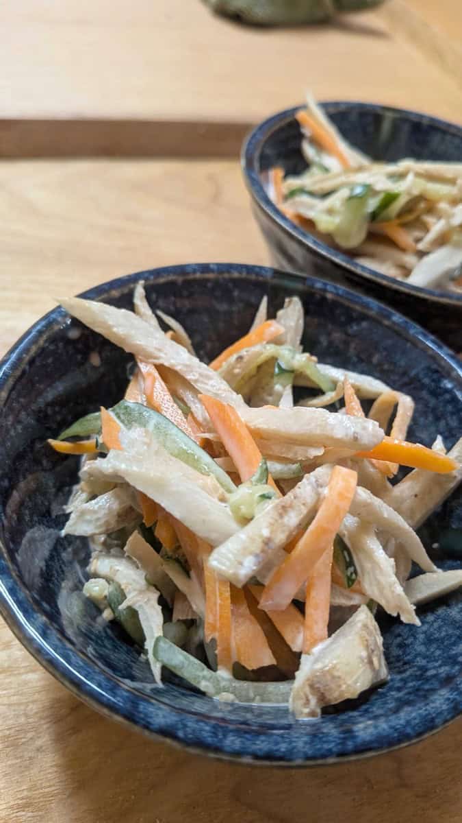 Japanese gobo salad with burdock root, carrot and cucumber in a mayonnaise dressing, served in two small navy blue bowls
