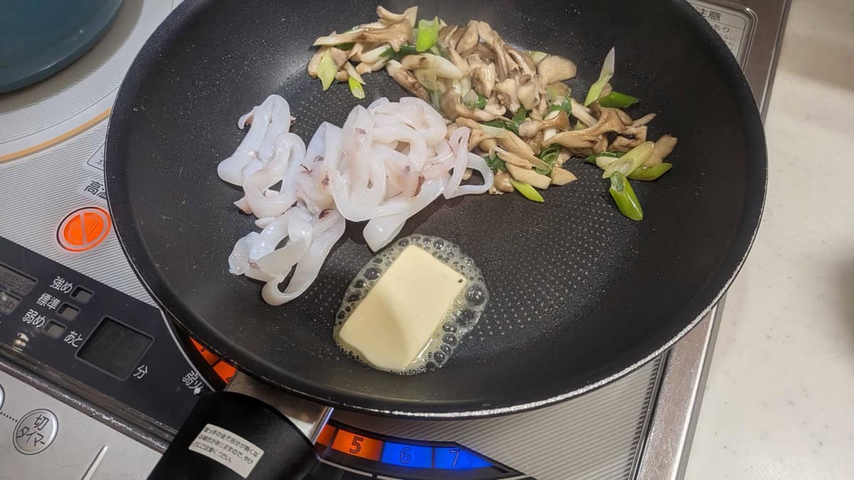Raw squid rings added to one side of the pan with a fresh pat of butter, the mushrooms pushed to the other side