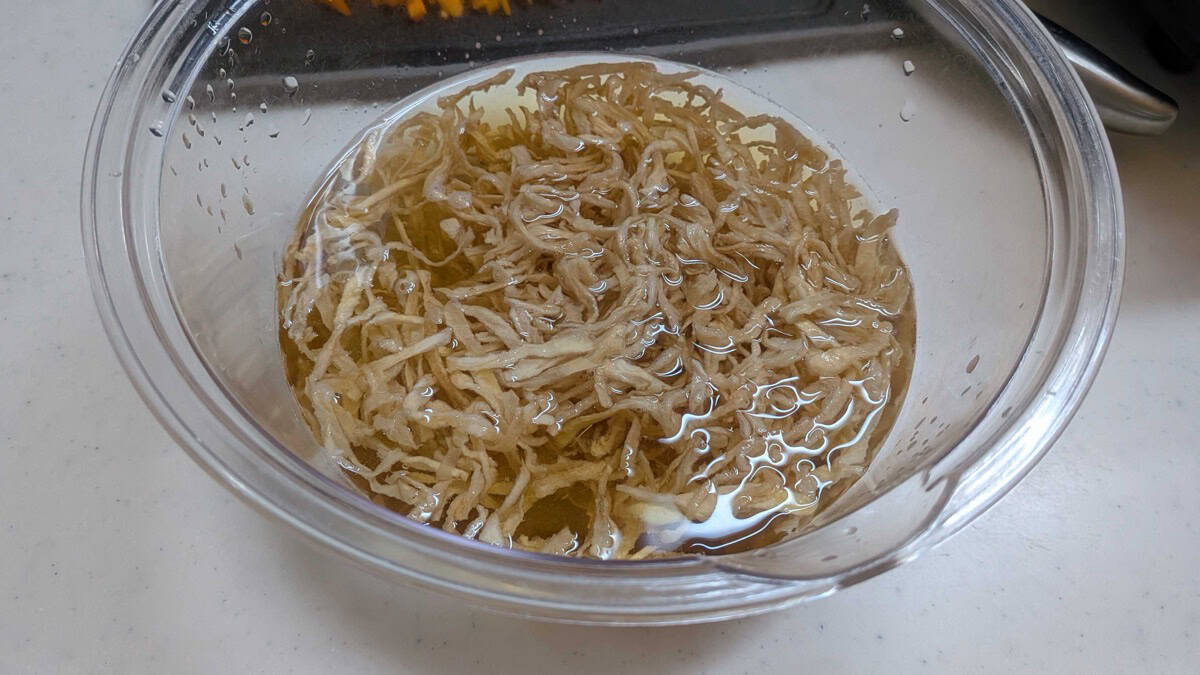 Rehydrated daikon strips swollen and soft in amber-colored soaking water