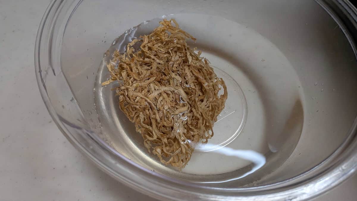 Dried daikon strips just covered with cold water in a glass bowl to rehydrate