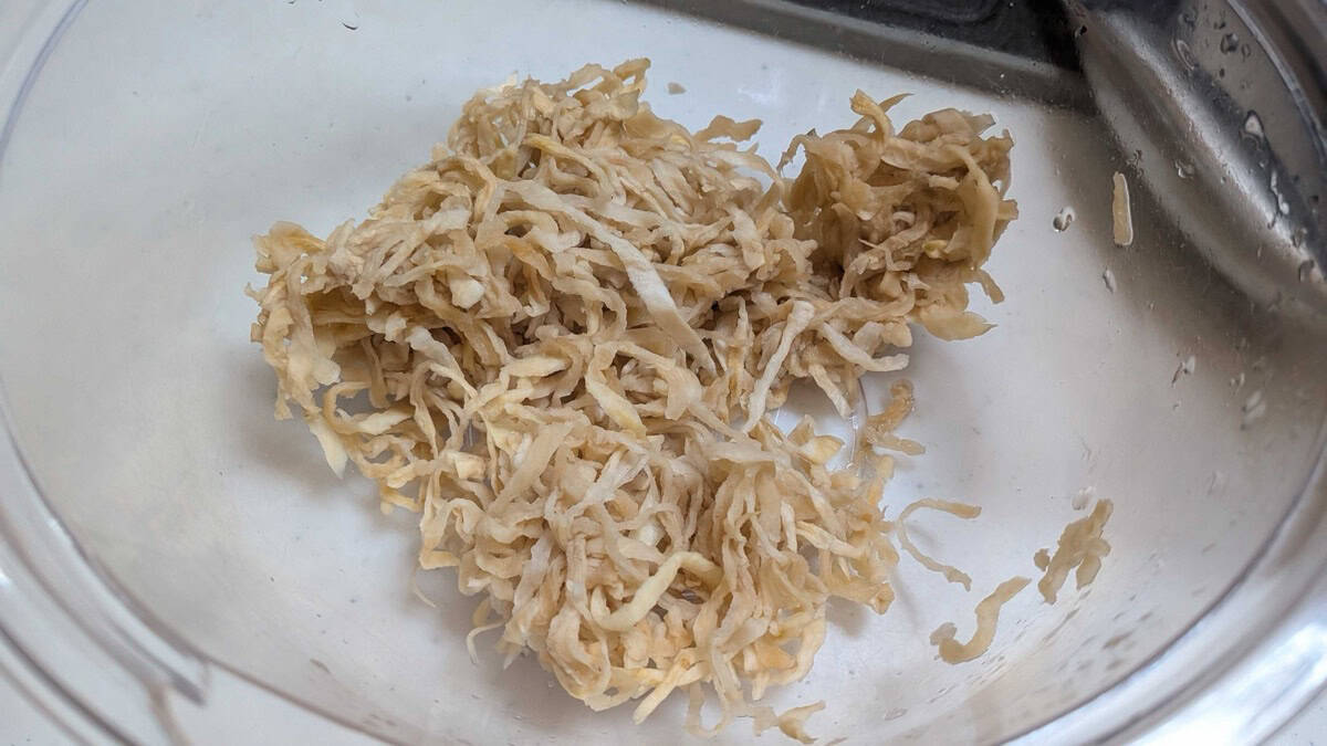 Rehydrated daikon squeezed dry and sitting in a glass bowl, ready to fry
