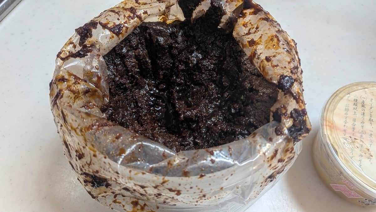 Close-up of homemade Japanese rice miso, very dark brown after long fermentation, in its plastic bag