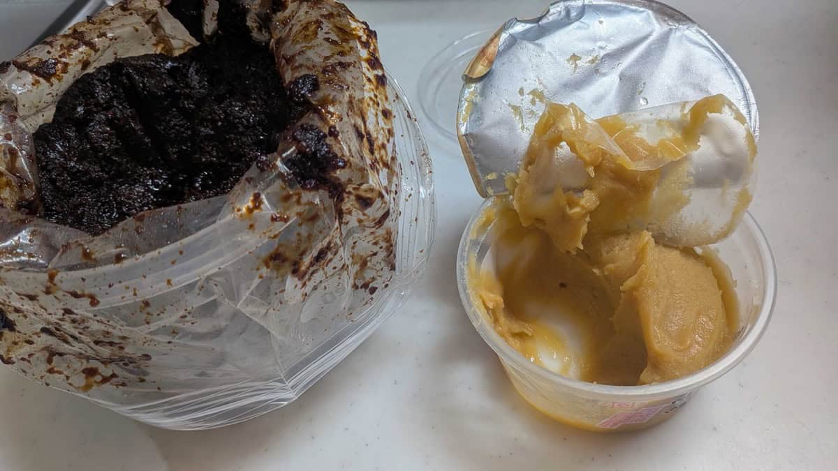 Dark homemade Japanese miso next to a tub of pale Kyoto shiro miso, showing the difference in color between long-fermented and short-fermented miso