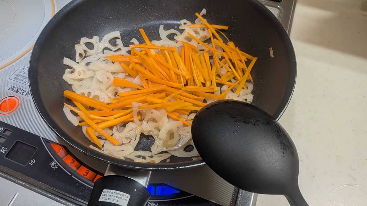 Julienned carrot added to the pan of stir-fried lotus root