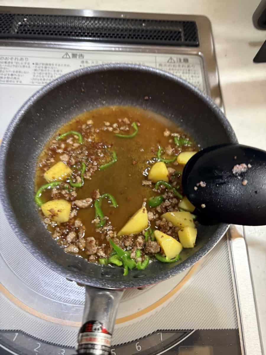 The mixed sauce poured into the pan, still thin and pooling around the pork and potato