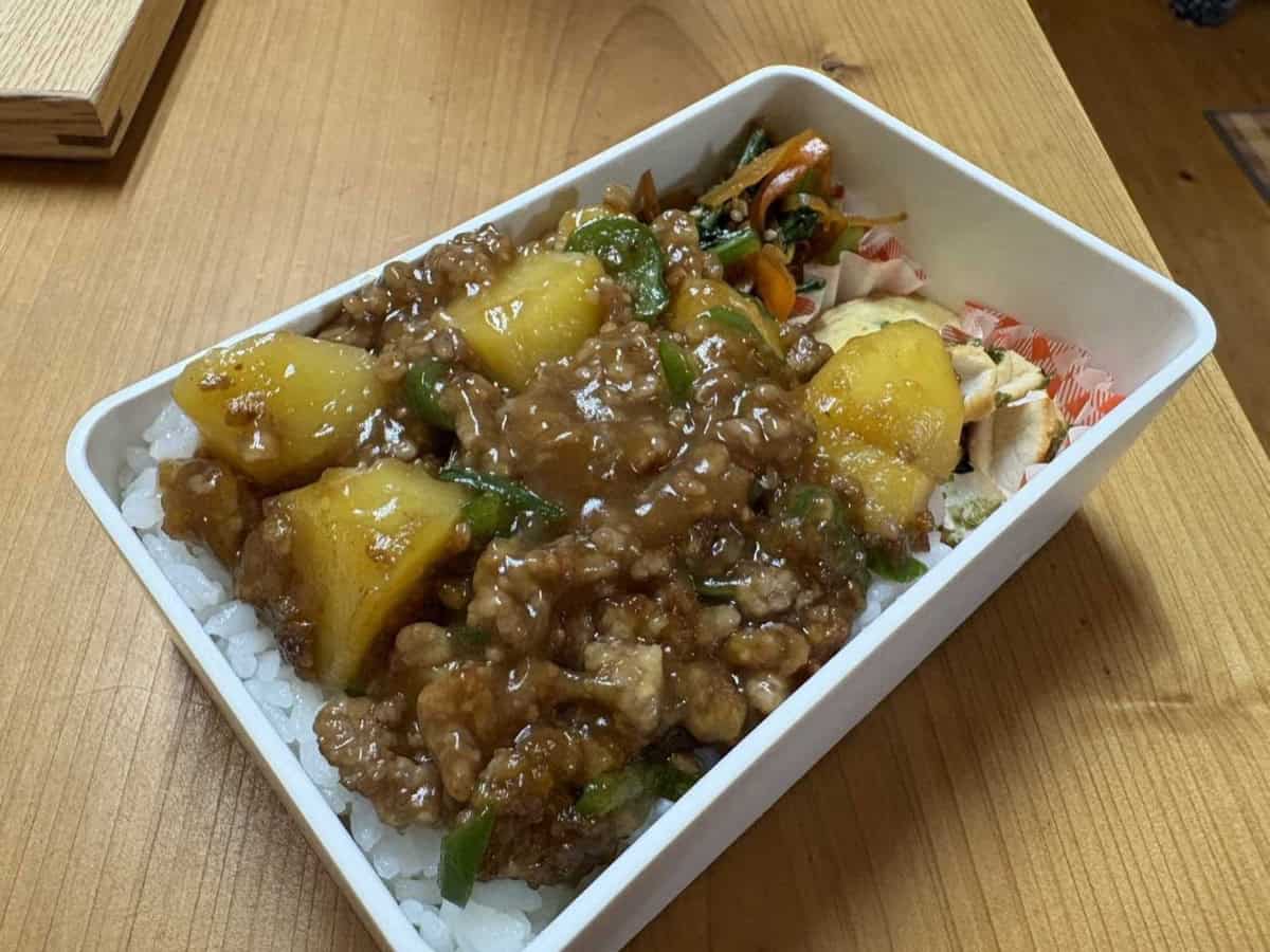 Close-up of the bento box showing the glossy soboro ankake sitting on top of the rice without soaking in