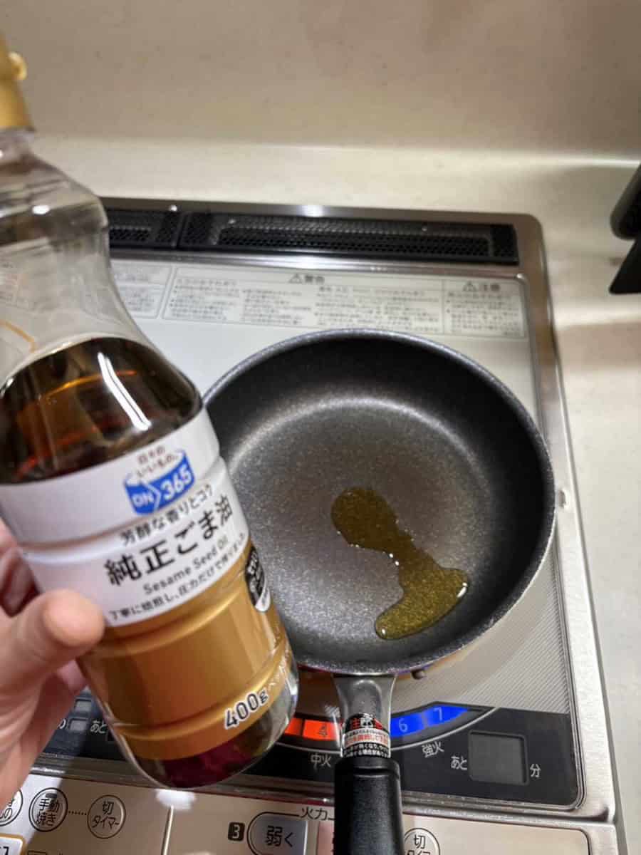 Toasted sesame oil being poured into a frying pan on an IH cooktop