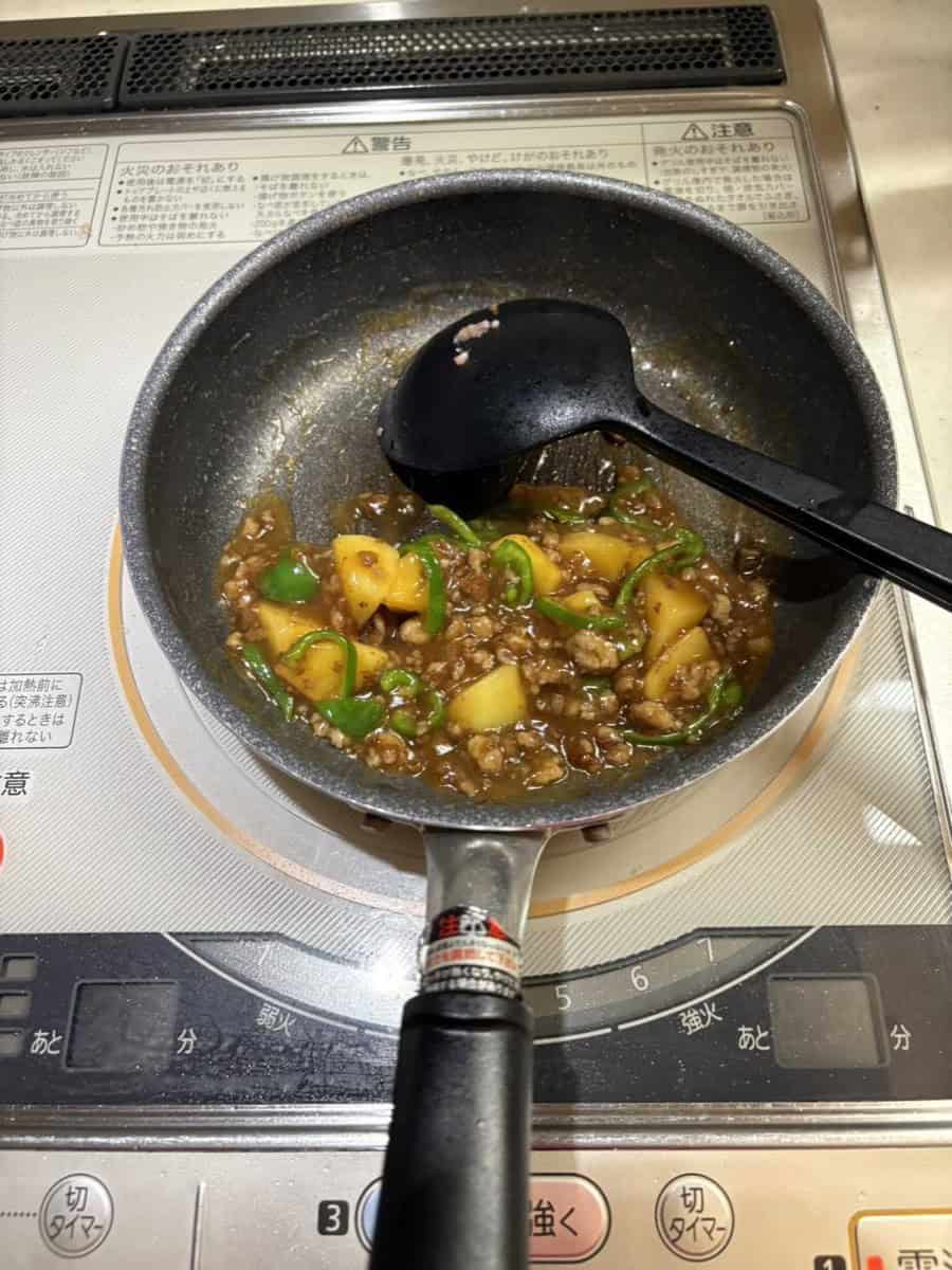 The finished soboro ankake in the pan, sauce thickened and glossy around the potato and pork