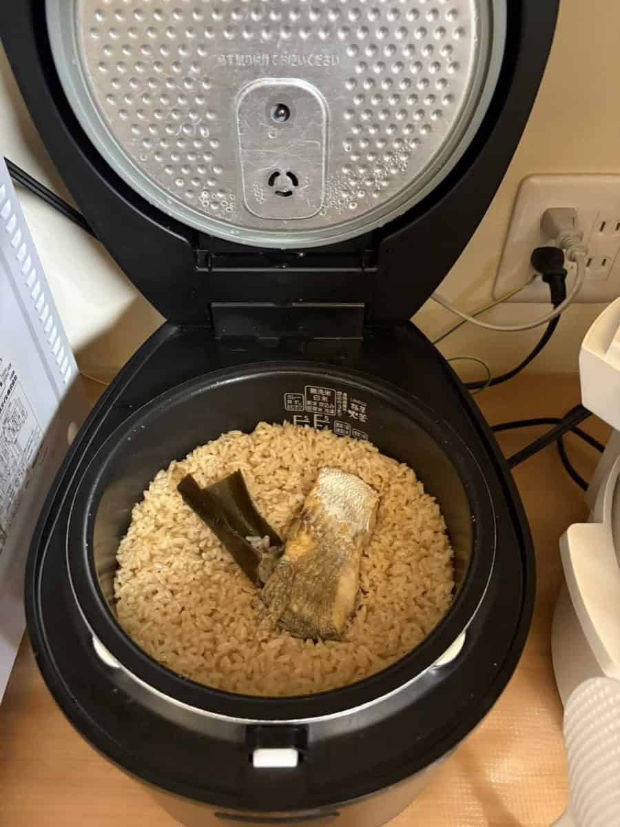 Cooked tai meshi in an open rice cooker with the sea bream fillet and softened kombu on top of the rice