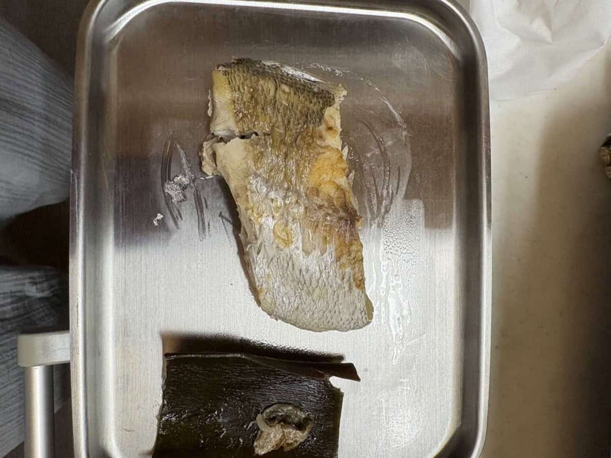 The cooked sea bream fillet and the softened kombu lifted out of the rice cooker onto a stainless steel tray