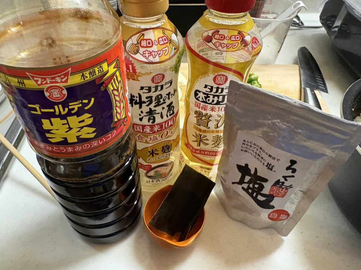 Japanese seasonings for tai meshi: a bottle of Kyushu soy sauce, cooking sake, mirin, a piece of kombu and a bag of salt