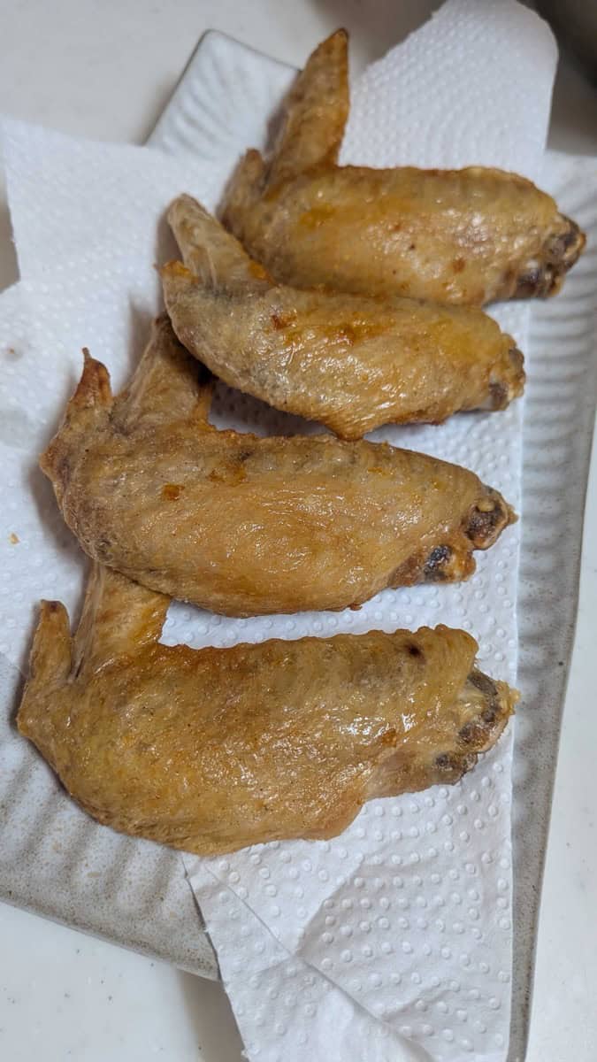 Close-up of air fryer Japanese chicken wings with thin crackly golden skin, resting on paper towel