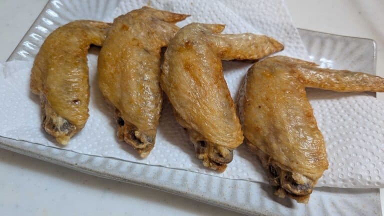 Air fryer Japanese chicken wings — four salt and pepper tebasaki with crisp golden skin on a white plate