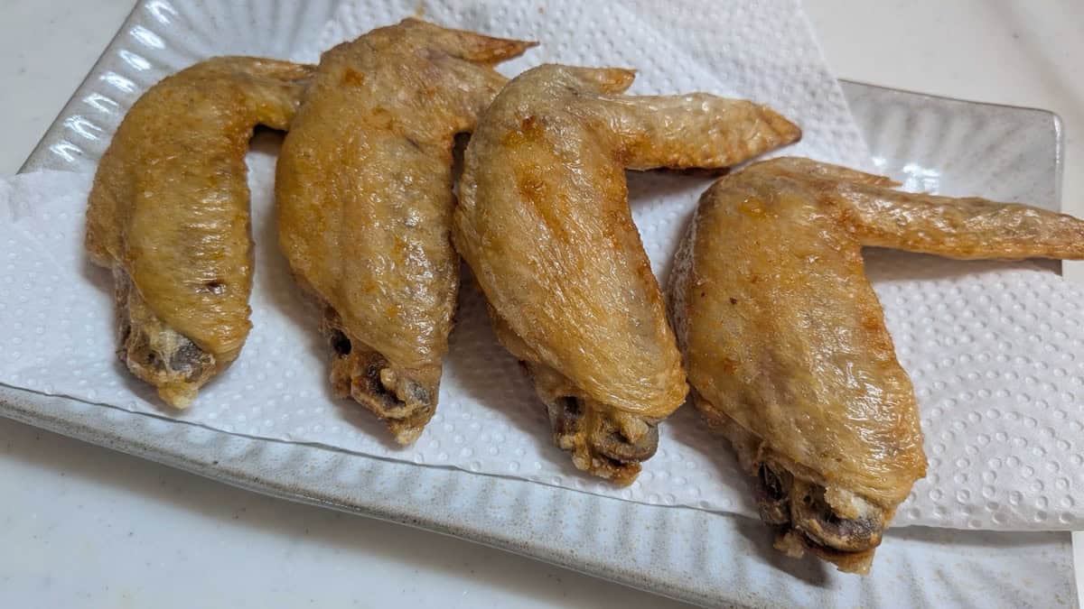 Air fryer Japanese chicken wings — four salt and pepper tebasaki with crisp golden skin on a white plate
