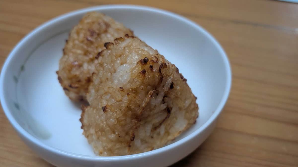 Two air fryer yaki onigiri on a white plate, showing the crunchy toasted rice grains on the surface