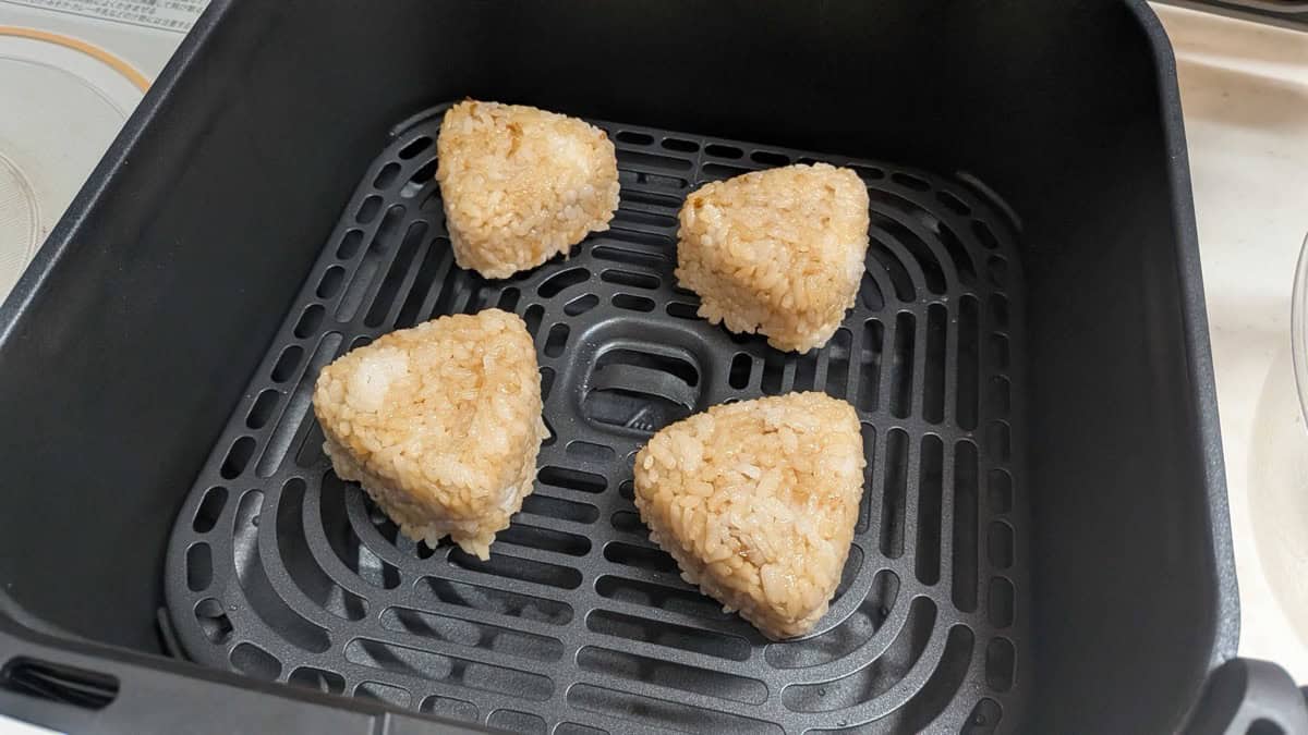 Four shaped yaki onigiri spaced out in the air fryer basket ready to cook