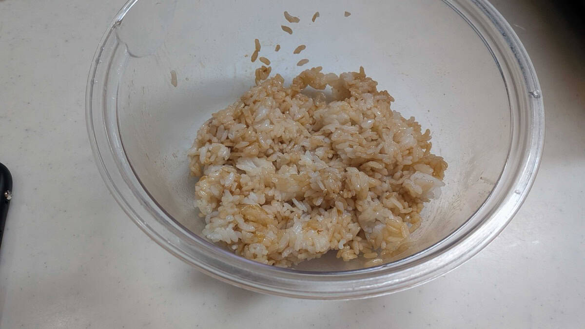 Rice mixed with soy sauce, mirin and bonito flakes until evenly light brown in a glass bowl