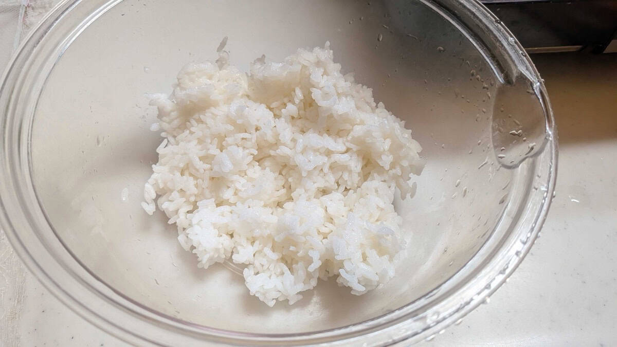 Warm cooked Japanese short-grain rice in a glass bowl on a kitchen counter